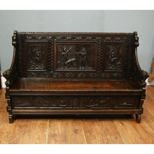 Impressive antique carved oak hall settle in the Renaissance Revival style featuring richly carved panels and bold...
