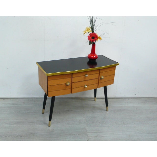 1950s hallway chest of drawers, with 2 doors and 2 drawers. The surface is black Formica, with gold-colored vinyl edging...