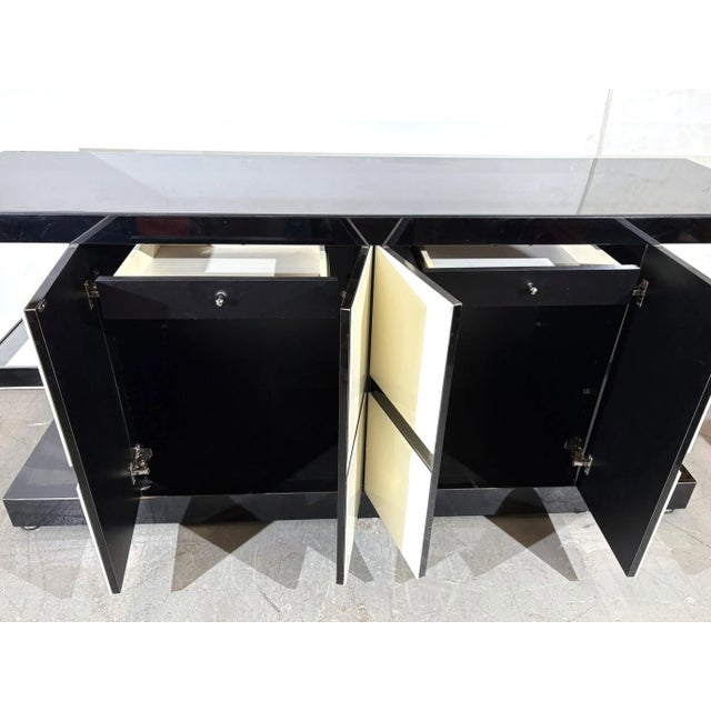 A modern Sideboard or Credenza. All the panels are black or milk glass on a wooden frame. There are 2 drawers behind the...