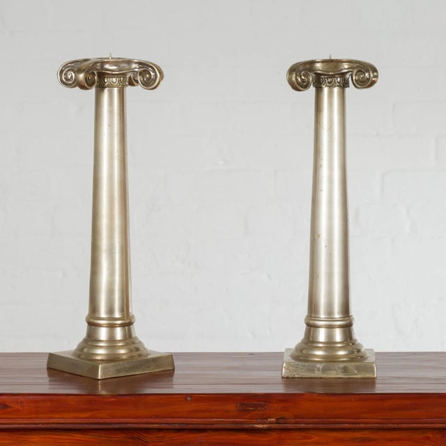 A pair of Thai brushed silver over bronze candlesticks from the mid 20th century, with Ionic capitals. Created during the...