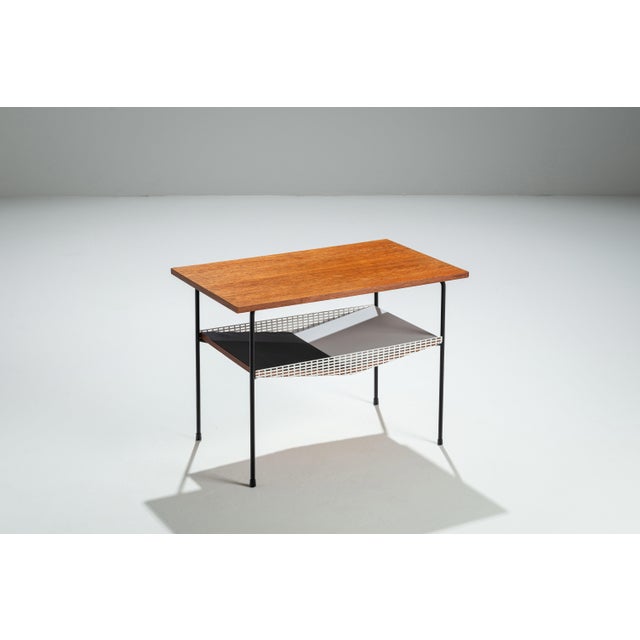 This contemporary side table brings together warm natural materials and bold modern design. Its teak top introduces a...