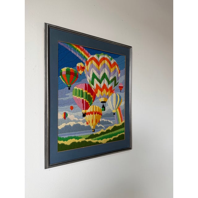 Charming 1982 vintage needlepoint embroidery artwork featuring a whimsical sky filled with colorful hot air balloons and a...