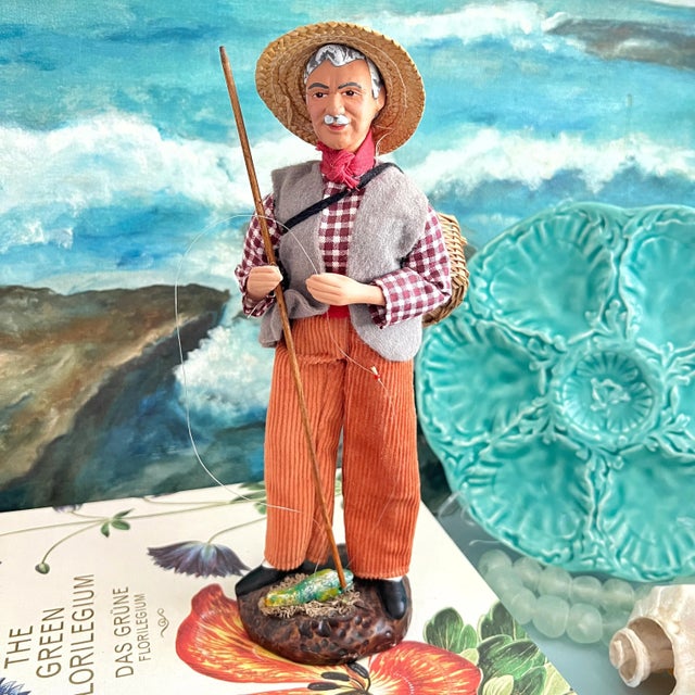 A French terra cotta santon of a fisherman with a basket of fish in traditional clothing. Santons are handpainted...