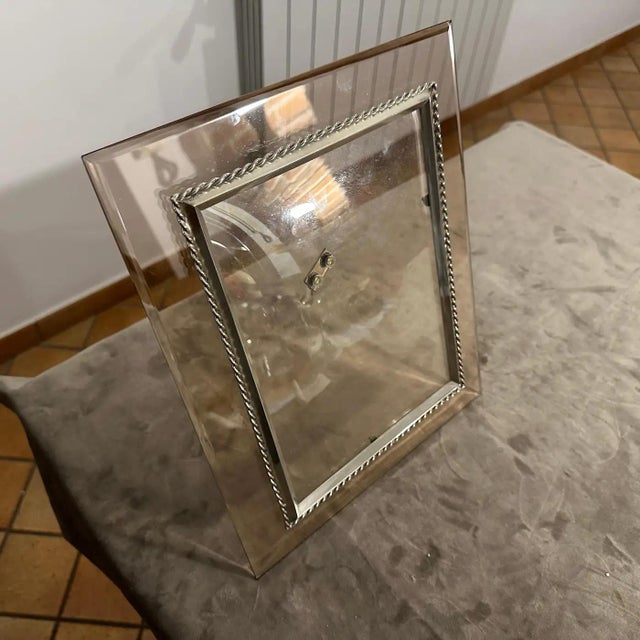 This is a mid-century modern picture frame crafted with a combination of smoked glass and silver-plated accents. The main...