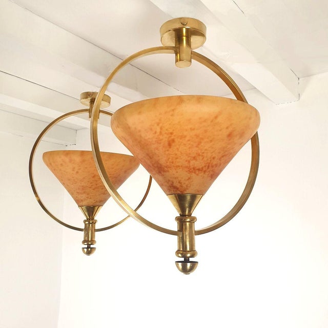 Pair of Mid-Century pendant chandeliers, France 1960s. The vintage lights are made of translucent amber glass paste and...