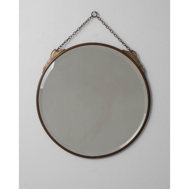 A circa 1920 French wall mirror featuring a bronze frame designed in the Art Deco style, with a focus on symmetry and...