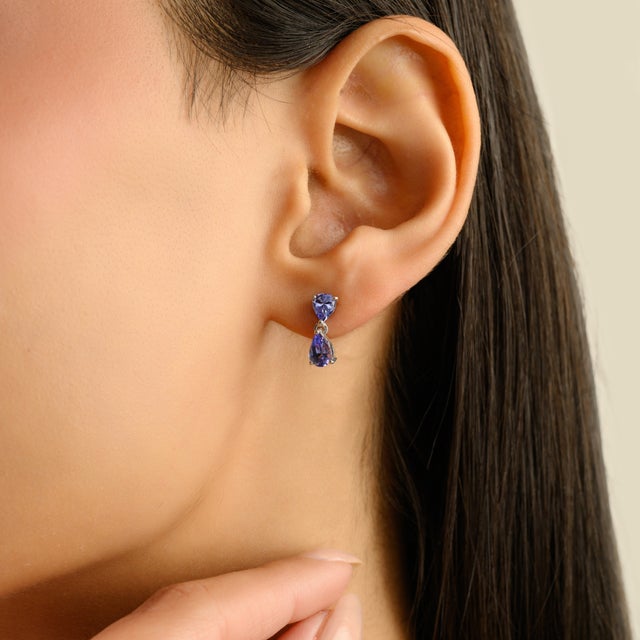 These refined sterling silver drop earrings feature luminous sapphires gemstones in elegant teardrop and trillion cuts....