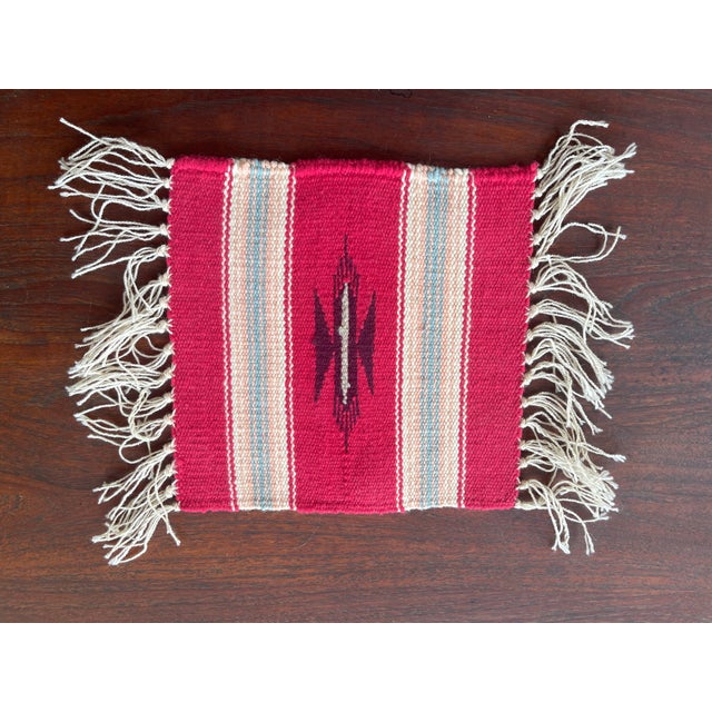 Vintage New Mexican wool Chimayo tapete weaving, maroon and beige central image, earth tone stripes. Background is navajo...