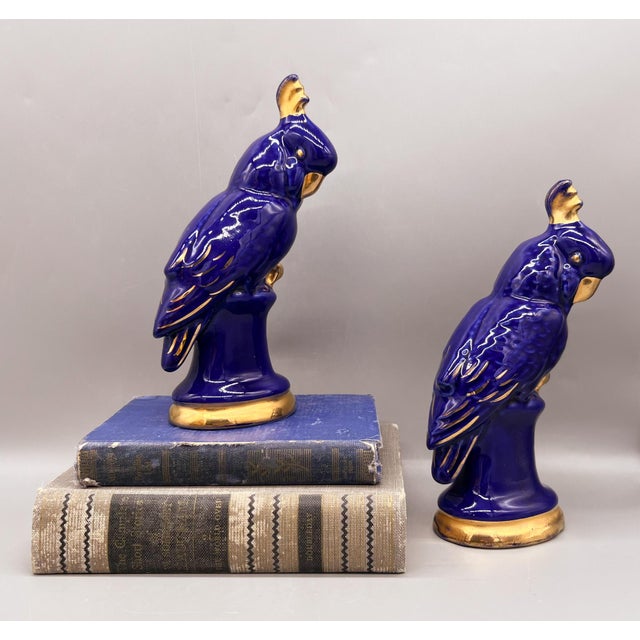 Brilliant and uncommon pair of blue cockatoos on perches with 22k gold accents. Made circa the mid 20th century and...