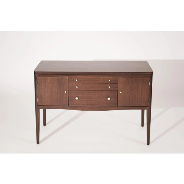 An outstanding console table executed in mahogany with brass hardware, three drawers, and side doors provide plenty of...