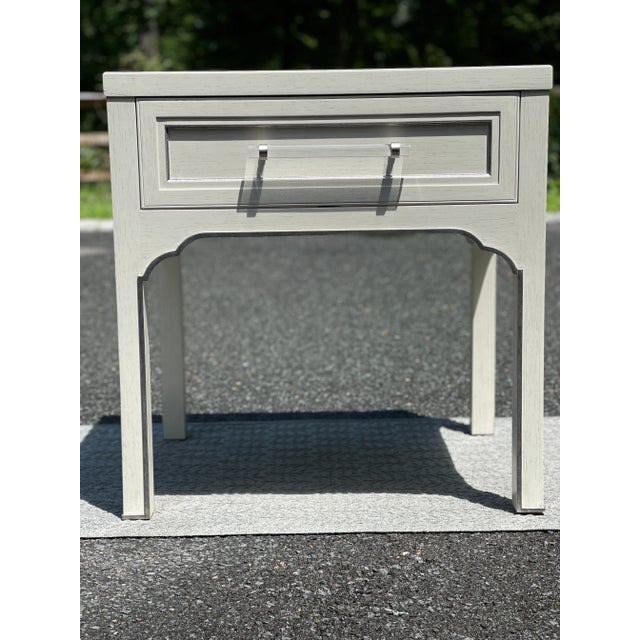 A rectangular framed top rests over four squared posts that flank a framed molded drawer accented by silver leaf stripes....