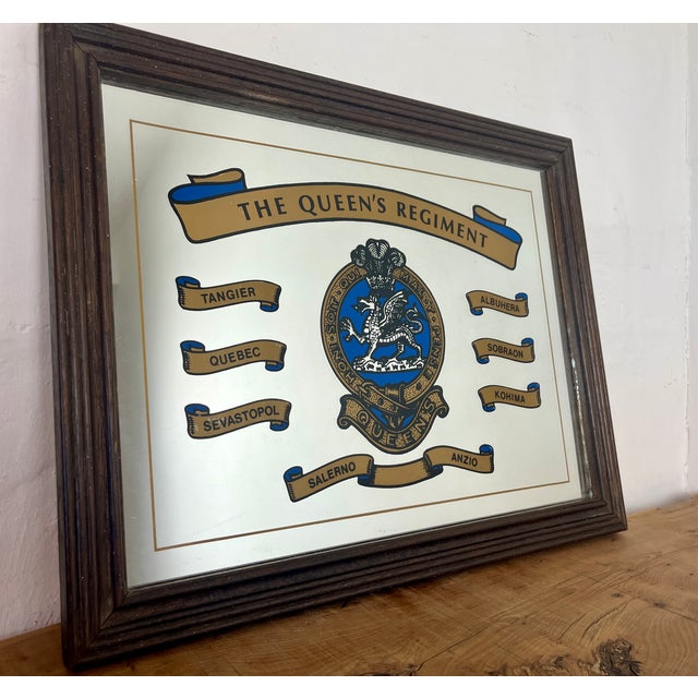 British vintage printed mirror featuring the insignia and battle honours of the British Army's The Queen's Regiment. The...