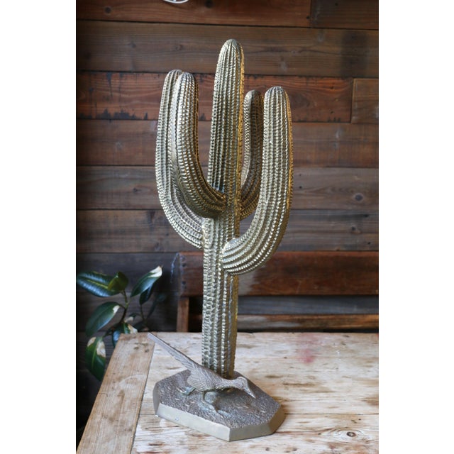 Wonderful large-scale brass sculpture depicting a classic saguaro cactus with an accompanying road runner at its base....