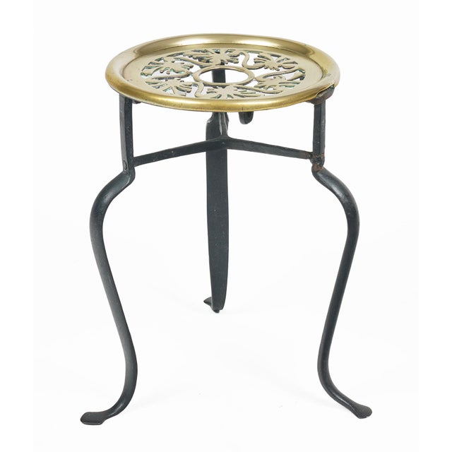 Victorian brass and iron trivet with pierced round top mounted on tall black cabriole shaped legs and penny feet.
