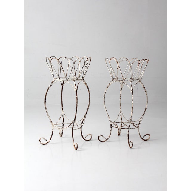 A charming pair of vintage metal plant stands featuring an open wirework form and softly scalloped rims. The looping lines...