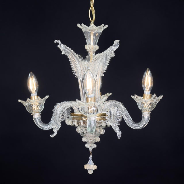 This handcrafted, gold-infused cristallo Murano floral chandelier features four undulating scroll arms holding bobeches...