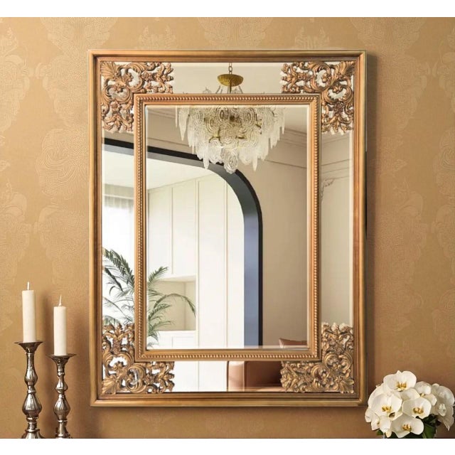 Make a dramatic statement with this ornate gold-finished wall mirror, featuring elaborate scrolling details inspired by...