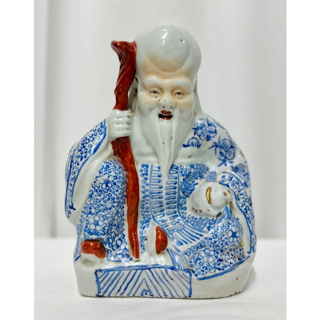 A character-rich porcelain figure depicting a smiling, long-bearded immortal—likely Shoulao (the Daoist god of...