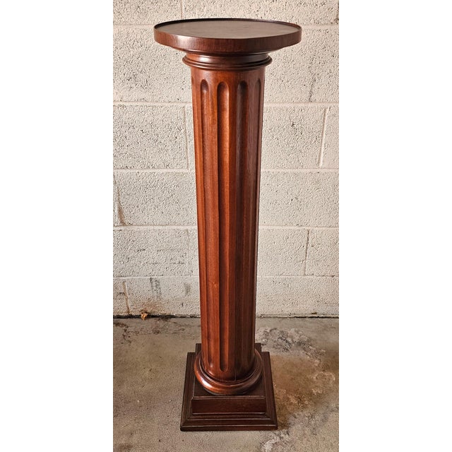 A 20th Century Mahogany Ionic Order Style Column-Form Pedestal Measures 10.5" in width, 10.5" in depth and stands 40.25"...