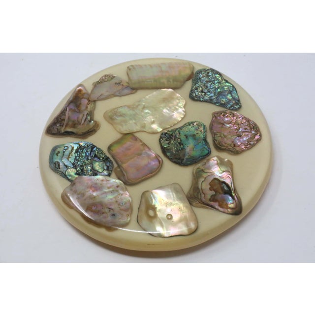 A vintage, 5 1/2" diameter acrylic trivet, embedded with iridescent, polished pieces of abalone shell. Good vintage...