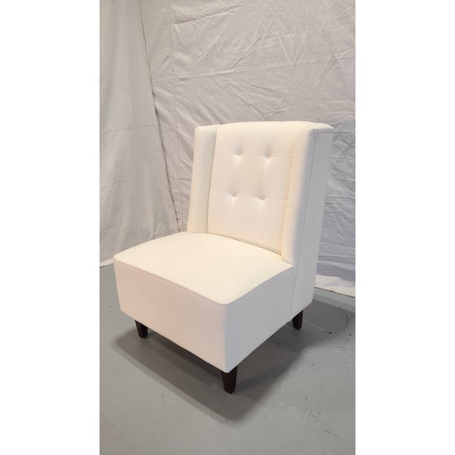 This white, armless side chair is sleek in design with a simple tufted back.