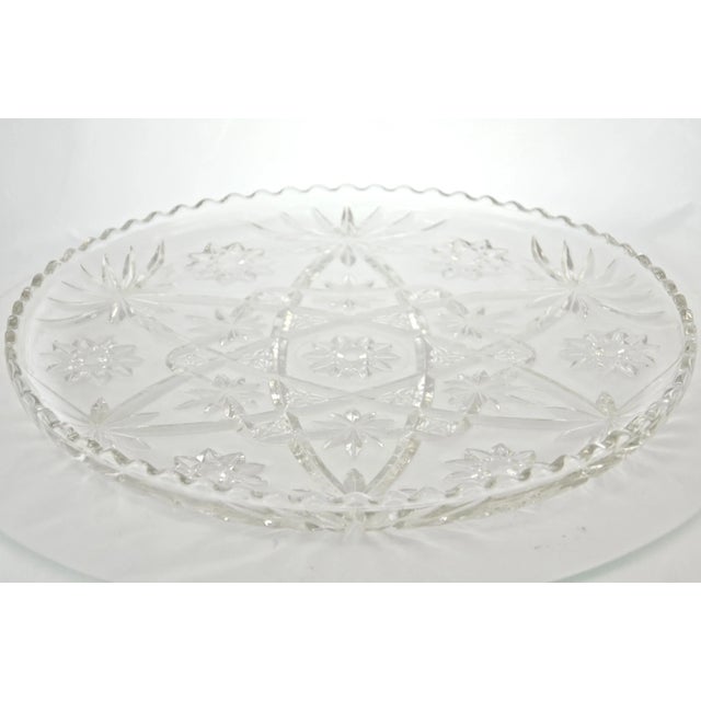 Large 13.5 inch round thick vintage glass tray with a shimmering sunburst and star center pattern and a scallop rim....