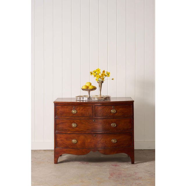 19th-century Victorian mahogany bowfront chest with four graduated drawers, cast brass urn hardware, and a warm aged...