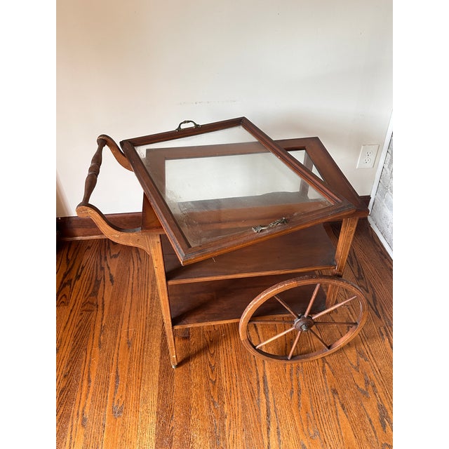 Traditional wood tea and bar cart with a removable framed glass tray, turned push handle, large spoked wheels and lower...