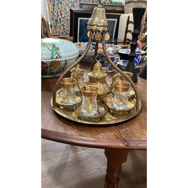 Beautiful vintage Turkish tea service featuring an ornate brass tray with a decorative carrying frame, matching teapot,...