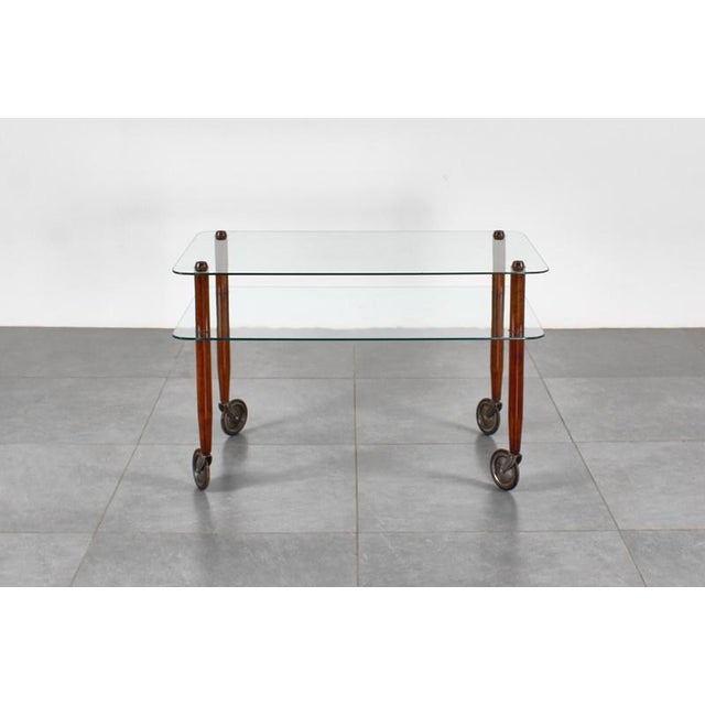 Prestigious coffee table on wheels, with turned wooden legs and a double Vitrex tempered glass top (sandblasted logo on...
