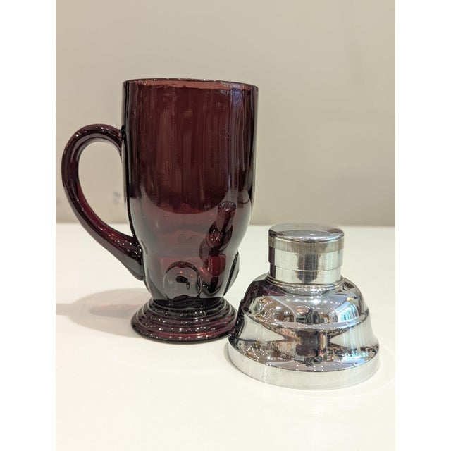 Vintage amethyst glass cocktail shaker featuring polished chrome hardware and an integrated side handle. Designed in the...