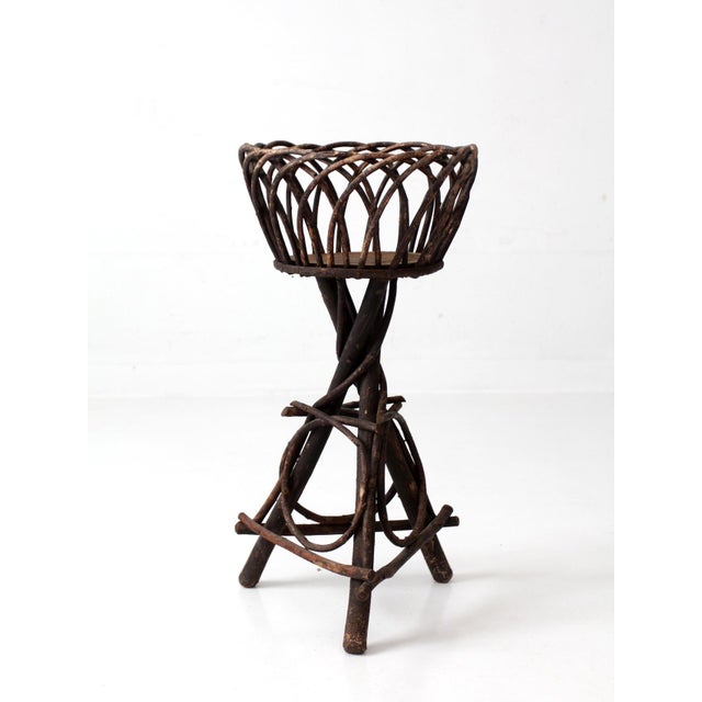 Vintage Adirondack twig plant stand featuring an open lattice basket, twisted branch supports, and a sculptural tripod...