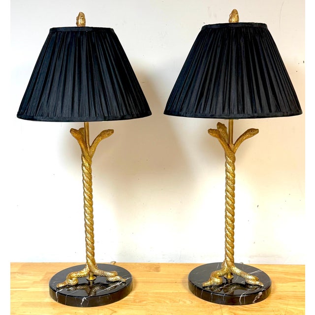 A striking pair of Italian Neoclassical-style gilt metal table lamps formed as three intertwined serpents, rising in a...