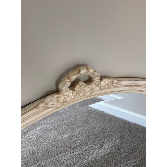 Elegant vintage oval wall mirror featuring a beautifully carved French Provincial inspired frame with delicate ribbon...