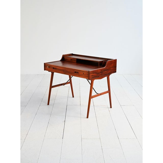 Rosewood desk with slender legs, drawer fronts, and a shelf with compartments and a small drawer. Produced by Vinde...
