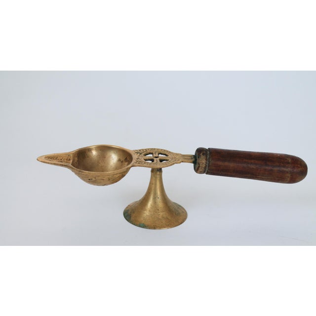 Vintage brass oil lamp or diya with a wooden handle, also known as an aarti lamp. It is a traditional item used in Hindu...