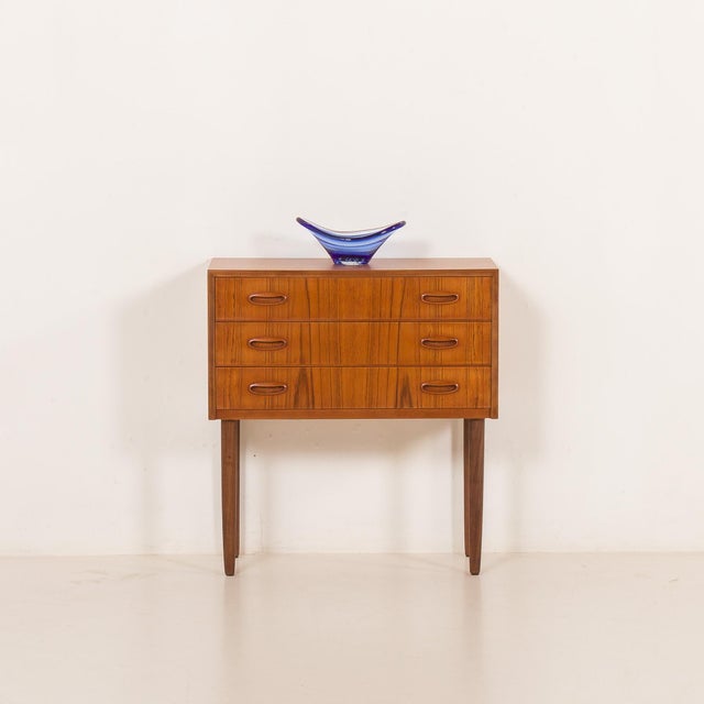Small Danish vintage teak dresser from the 1960s. It features three drawers with beautifully curved solid teak handles,...