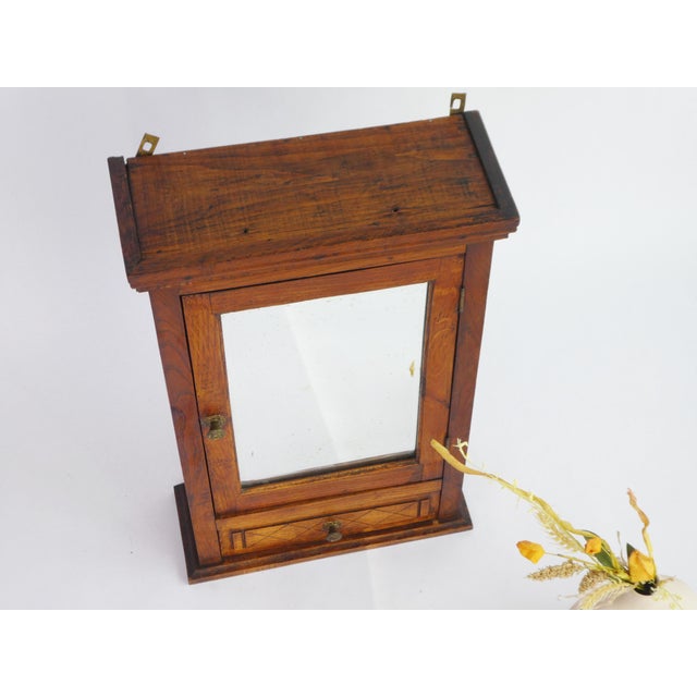 Small Art Deco antique wooden cabinet with a beveled rectangular mirror in the front door. The apothecary has beautiful...