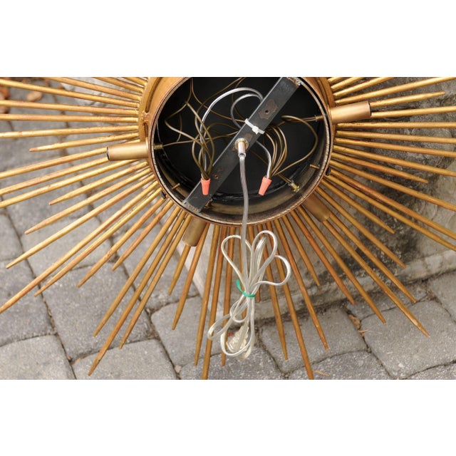 A French vintage gilt metal sunburst light fixture from the mid-20th century, with central mirror and new wiring. We...