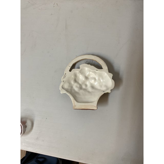 Vintage decorative ceramic wall plaque featuring a sculptural fruit basket design with richly colored grapes, pears, and...