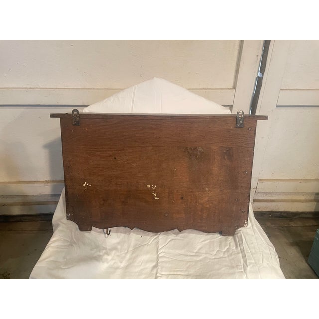 Wall mounted wooden shelf with scalloped edges and. dark finish. The piece includes two brass hooks in a vintage style...