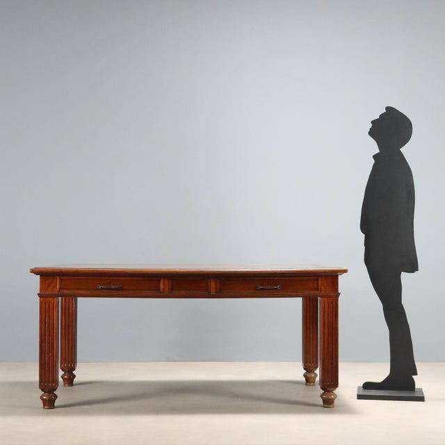 Walnut desk. Paneled top with brown leather insert, pair of drawers in the lower section, carved square legs and turned...