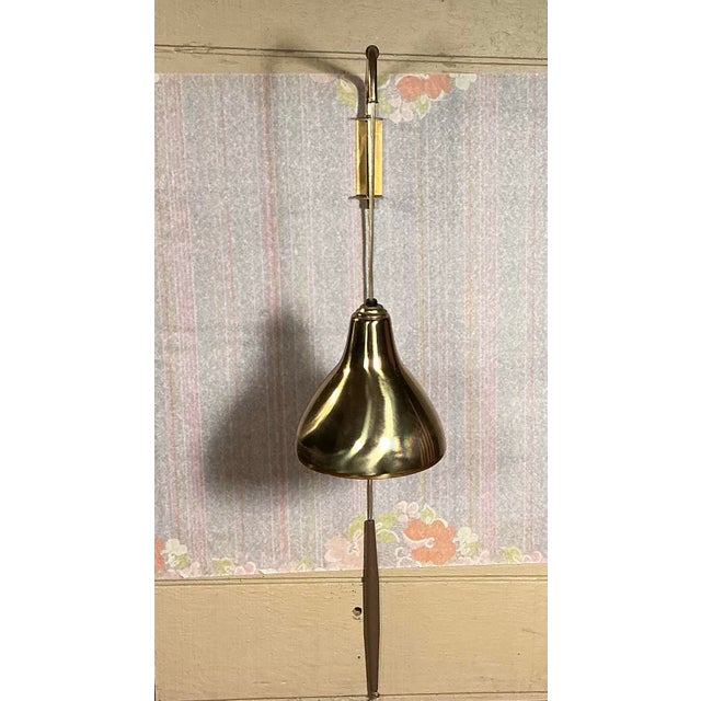 Mid-Century Modern telescopic arm wall lamp. Features bell shape brass shade, counter weight, telescopic arm allowing it...