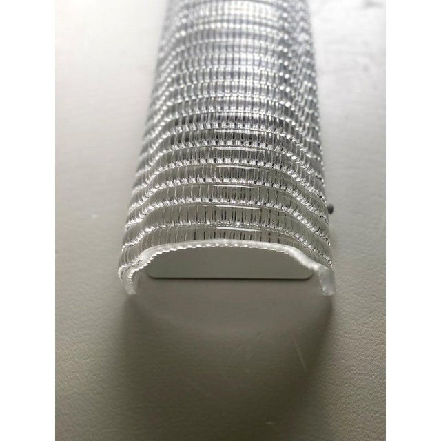 Contemporary wall sconce made in clear murano glass with a modern texture that give it bright . Made with a traditional...
