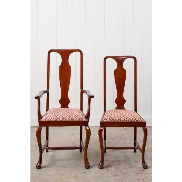 This set of eight walnut Queen Anne style dining chairs features cabriole legs with pad feet and turned stretchers. The...