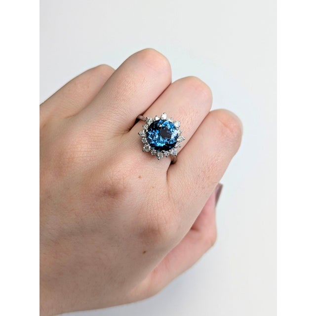 A London blue topaz rests in a deep, steely blue at the centre of this solid 14K white gold ring, encircled by sixteen...