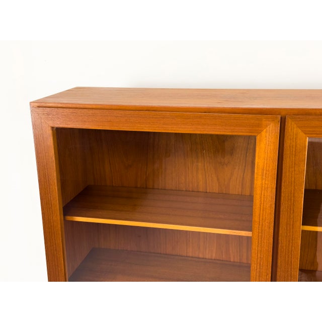 High-quality mid-century display cabinet by Omann Jun from the 1960s. Teak-veneered body with solid teak and glass doors....