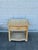 Vintage wicker nightstand in a natural beige-tan finish, featuring a woven rectangular top, single drawer with a matching...