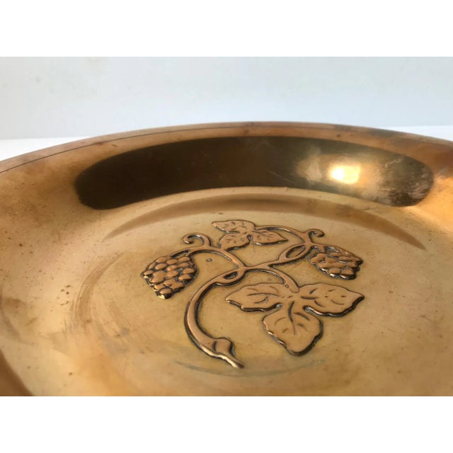 Polished bronze bowl with center-motif of grapes in relief. Designed and manufactured by Ægte Ildfast in Denmark during...