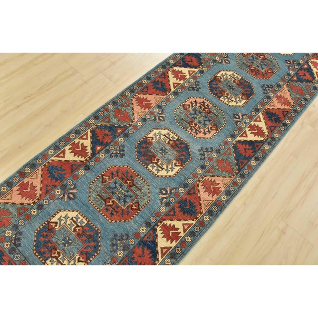 A tribal Caucasian Kazak runner hand-knotted with an all-wool pile on a cotton foundation. This oriental rug features a...